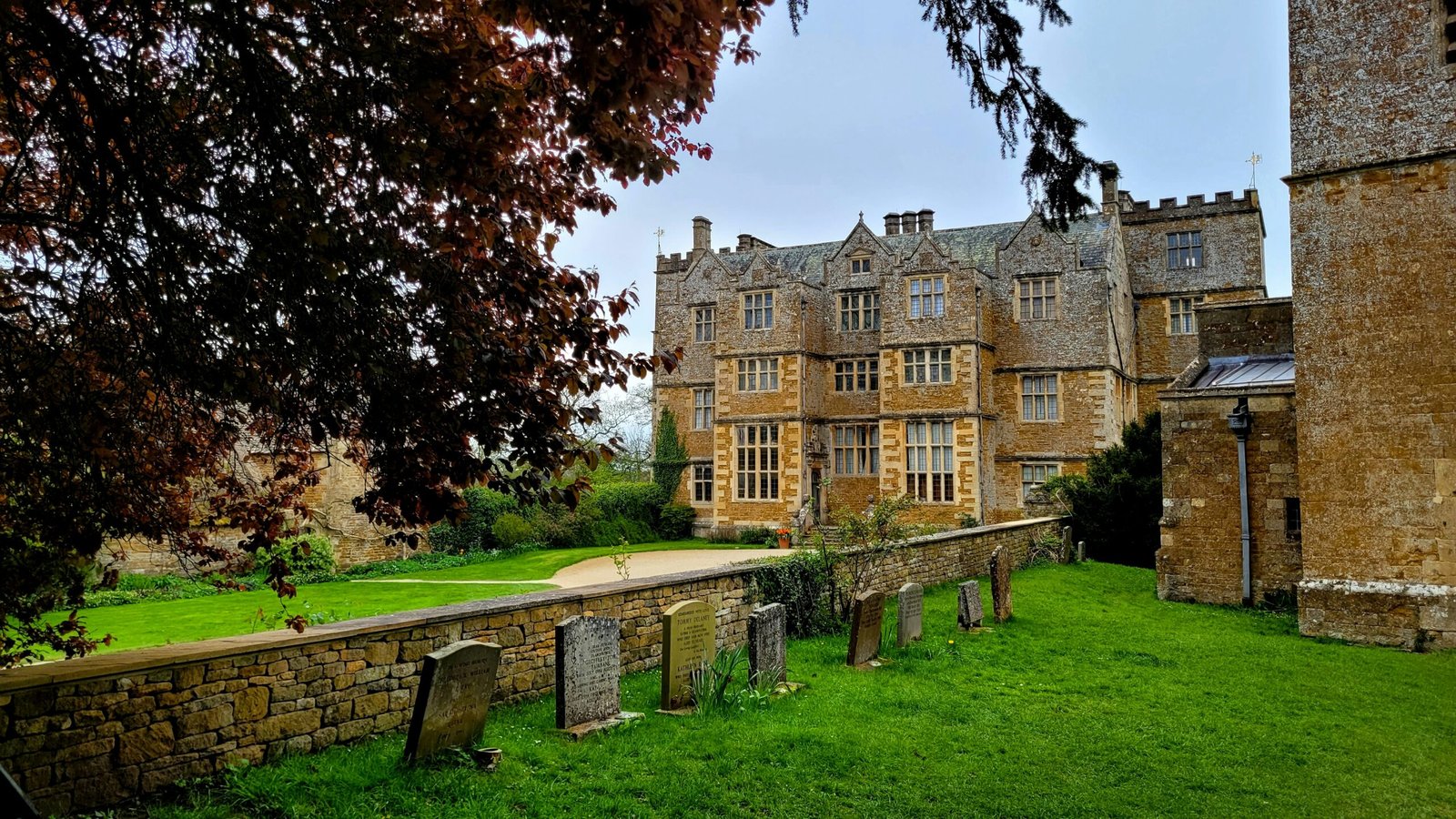 A manor house with a graveyard in the foreground